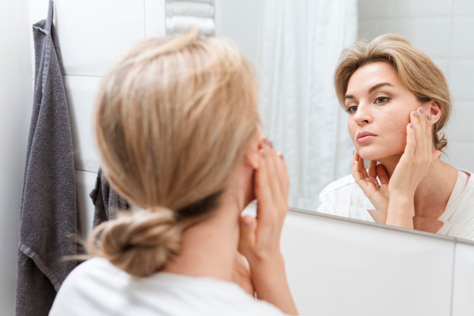 Woman in a bathroom checking herself in the mirror